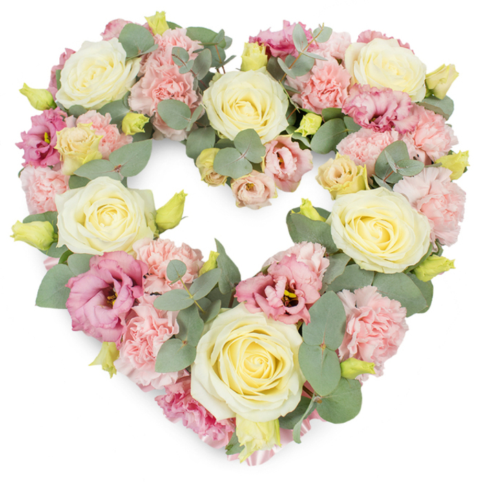 A luxurious heart-shaped floral wreath, crafted with the care of an experienced local florist, is pictured against a bright white background, its pastel hues standing out with clarity and calm. The heart is densely filled, with no bare spaces, suggesting both abundance and a deep, unwavering affection. Large cream and light butter-yellow roses are positioned at intervals around the outline, their full, velvety blooms echoing one another and anchoring the composition with gentle symmetry. Between these focal roses, soft pink carnations gather in rounded clusters, their tiny, frilled petals catching the light and introducing delicate texture that feels almost like lace. Threaded among them are elegant lisianthus blooms in richer pink and mauve tones, some fully opened into graceful cups, others slightly closed, hinting at unfolding stories and memories. These deeper shades add visual rhythm to the wreath, guiding the eye around the curve of the heart. Interwoven through the flowers, stems of silvery-green eucalyptus create a soft halo of foliage; their rounded leaves curve naturally along the contours, enhancing the heart shape and lending a cool, calming note in contrast to the warm pastels. Here and there, small yellow-green buds nestle at the base of the blooms, subtle signs of freshness and attentive floristry. The arrangement radiates a mood of peace, sympathy, and enduring love, perfectly suited to a farewell service in Clerkenwell, perhaps in one of the area's historic churches or crematoria. It feels like a quiet, dignified tribute that could be delivered from a trusted Clerkenwell florist, a comforting presence beside a coffin or memorial photograph, speaking softly of cherished memories and heartfelt goodbyes.