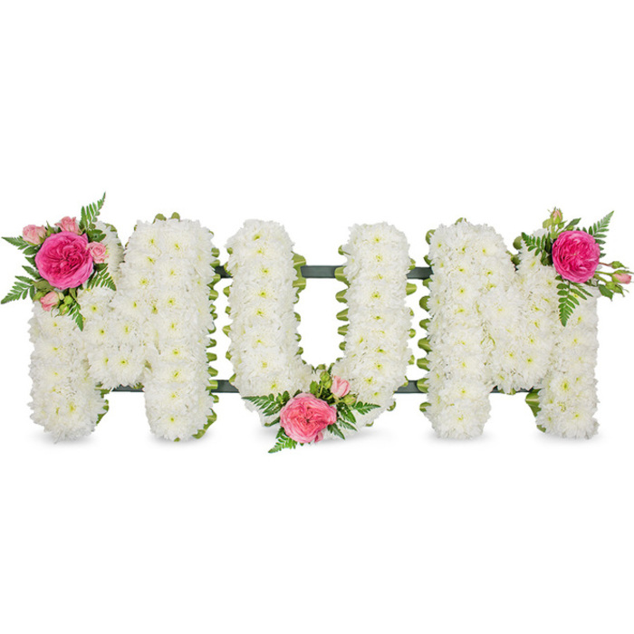 The image presents a large, traditional MUM funeral tribute crafted with a precision that suggests an experienced local florist's hand. Set against a plain white background, each capital letter stands out clearly, supported by a slim but sturdy dark green frame that runs discreetly along the base. The letters themselves are completely encrusted with small white chrysanthemums, each bloom carefully angled so that the petals create a smooth, domed surface with a soft, cushion-like appearance. From a distance the letters read as pure white, but close inspection reveals the natural cream and lime tints at the flower centres, adding gentle depth. Colour is introduced through three carefully positioned clusters of focal flowers. On the upper left of the first M, a vivid fuchsia rose opens wide, framed by lighter pink spray roses and buds, with fine, lacy fern foliage and glossy green leaves giving a natural, garden-fresh feel. A second cluster sits in the lower curve of the U, drawing the gaze toward the middle of the tribute, while the third caps the upper right of the second M, completing a subtle diagonal line of pinks across the design. The foliage spills just beyond the crisp outlines of the letters, softening the structure and adding a sense of movement. Everything is sharply lit, with no harsh shadows, emphasising freshness and clarity-exactly the kind of refined memorial piece often prepared for services in Clerkenwell, near landmarks such as Spa Fields or Sadler's Wells. This MUM tribute would suit a funeral, memorial, or cremation service where family wish to convey enduring respect and a heartfelt farewell through traditional white flowers lifted by touches of tender pink.