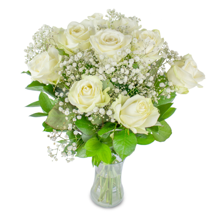 This bouquet's language is gentle sophistication: twelve or so ivory-white roses form the central rhythm, each blossom a study in soft curves and layered petals-some wide open like little cups, others still coiled and private-creating a sense of living motion. Interwoven among them are clouds of delicate baby's breath (Gypsophila), their tiny stars of white knitting the arrangement together and lending it an airy, lace-like veil. Rich green foliage beneath the blooms supplies both colour contrast and quiet strength; the leaves' satin surfaces catch the light and anchor the bouquet's vertical lines. The stems are visible through a simple, clear glass vase, the water level and trimmed ends speaking of careful conditioning and immediate freshness. Against a plain white backdrop the composition feels both modern and timeless, every texture defined-the velvety petals, the whispering sprays of gypsophila, the cool clarity of glass. There is a subtle, refined scent-barely there, like a memory-which pairs naturally with ceremonial settings, milestone anniversaries, or moments of remembrance. As a florist who arranges pieces for ceremonies and home deliveries around Clerkenwell Green and Spa Fields, I choose this restrained palette when the occasion calls for calm elegance rather than spectacle. Placed on a mantel or a small round table by a window on Cowcross Street, it reads as a quiet declaration of care: composed, luminous, and thoughtfully made.