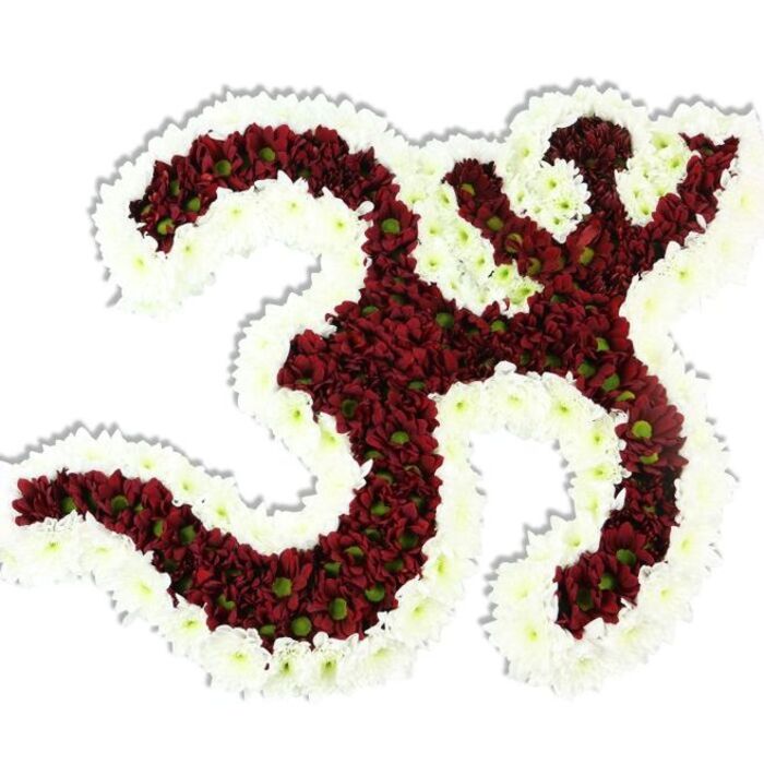 A meticulously fashioned floral Om (Aum) symbol appears against a stark white background, its iconic Sanskrit silhouette rendered in tight clusters of deep maroon-to-burgundy chrysanthemum-like pompons. Each small red bloom shows a pale lime-green centre that punctuates the dark field with tiny glints of life. Surrounding and defining the symbol is a thick, flowing border of immaculate white spray chrysanthemums; this white outline winds through the loops and negative spaces, sharpening the Om's curves and creating a clear, reverent contrast. A subtle drop shadow beneath the work reinforces its three-dimensional, hand-assembled presence and draws attention to the sculptural care of its construction.

Tactile detail matters here: the maroon pompons form a plush, velvety surface while the white sprays read as light and feathery, together producing a composed texture that invites close looking. The lighting is soft and even, bringing out the depth of the burgundy tones without flattening the delicate lime centres. There is a hushed, earthy aroma suggested by the chrysanthemums, lending the piece a calming, contemplative character suited to devotional settings.

As created by a Clerkenwell florist familiar with the area from St John Street to Spa Fields, this arrangement-offered for local ceremonies and quiet memorials across Clerkenwell and neighbouring Farringdon-serves as a dignified tribute for spiritual gatherings, meditation events, or community commemorations. Crafted with balanced proportion and floral precision by Clerkenwell Flowers, it honours the Om's symbolic resonance with grace and local care.