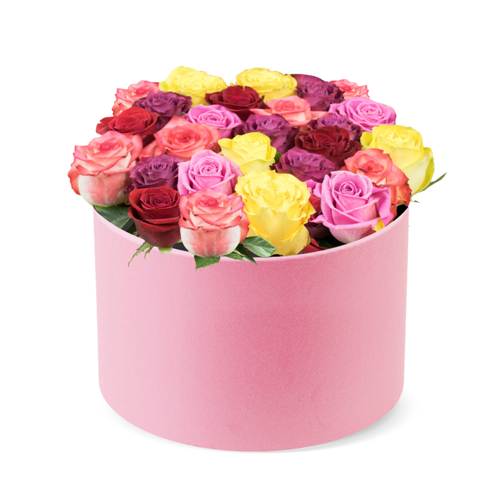 A stunning, luxurious floral arrangement sits within a soft pink, round hat box, set before a clean white background. The cylindrical container is wrapped in a velvet-like material, its top edge slightly curved to reveal a dense display of roses. Approximately thirty to forty individual blooms rise in a lush, domed centerpiece, packed tightly to create a full, opulent silhouette. The roses showcase a rich palette: bright yellow, deep red and burgundy, various pinks from blush to fuchsia, creamy-toned petals, and even regal purple-plum tones. Each bloom appears impeccably opened, its petals smooth and layered, with a crisp freshness suggesting peak season harvests. A scattering of vibrant green leaves peeks through, adding depth and a natural counterpoint to the candy-coloured petals. This box radiates premium gifting, suitable for Valentine's Day, anniversaries, birthdays, or Mother's Day, and it reads as a sophisticated touch for modern interiors. It's ideal for delivery to homes in Clerkenwell, Farringdon, or King's Cross-adjacent wards, offering a reliable option for central London celebrations or thoughtful surprises. Craftsmanship is evident in every detail-the careful density of blooms, the seamless curve of the box, and the fragrant bouquet that fills the room with rose perfume and hints of citrus. The composition is contemporary yet timeless, balancing lush abundance with refined restraint. It's the kind of arrangement that suggests a bespoke mood, perfect for professional settings or intimate moments alike. Viewed up close, the velvet texture catches the light like a soft blush, inviting the touch of fingertips and the memory of a summer garden. In Clerkenwell and the surrounding lanes near Clerkenwell Green, such bouquets harmonize with historic façades and modern cafés, a reminder that flowers carry local stories as well as beauty.