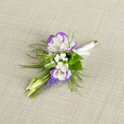 Displayed on a soft, woven light beige linen background that recalls the calm textures of Clerkenwell loft apartments, this refined boutonniere looks as though it has been composed petal by petal in careful silence. Two white lisianthus blooms form the focal point, their gently ruffled petals edged in a rich, royal purple that deepens towards the tips, creating a striking halo effect. The white centres glow softly against the neutral fabric, like early morning light along Clerkenwell Road. Nestled around them are tiny tufts of crisp white filler flowers, similar to baby's breath, which scatter a delicate, airy texture through the design and soften the bold bi-colour edges. Rising alongside these is a slender spike of muscari, its tiny, tightly clustered bell-shaped flowers a deep grape-purple, adding vertical interest and a slightly wild garden feel, as though it had been snipped from a spring border in a hidden courtyard off St John Street. Fine, feathery greenery, reminiscent of asparagus fern, extends in gentle sprays, framing the main blooms and giving the arrangement a sense of light movement and freshness. Two pale green buds tuck into the composition, promising future blossoms and a quiet sense of new beginnings, perfect for a wedding or civil ceremony. At the base, the stems are gathered neatly and wrapped in a smooth white satin ribbon, secured with a discreet bow that signals readiness for a lapel. The overall mood is serene, elegant, and intimate-an understated floral accent that would sit beautifully on the jacket of a groom, groomsman, or prom guest celebrating somewhere around Clerkenwell's historic streets.