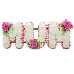 A quiet, carefully composed floral tribute that spells out MUM in large, connected capital letters, shown against a stark white background so every detail is visible. Each letter is formed from a dense carpet of pure white chrysanthemums, their small, layered petals creating a plush, uniform surface that suggests tranquillity and reverence. The outer contours are wrapped in a soft, ruffled pale-pink ribbon or fabric trim that warms the palette and adds a subtle, motherly embrace to the shapes. Between the letters a dark green structural frame is just visible, giving the standing piece a poised, architectural line. Visual focal points are three matching clusters of accent blooms: rich fuchsia-pink roses in varying stages of bloom sit at the top left of the first M, in the base curve of the U, and at the top right of the final M, each accompanied by glossy green fern-style foliage and small, reddish-orange hypericum berries that pick up light and add gentle contrast. The composition balances purity and affection - white for remembrance, pink for warmth - and the textures range from the papery chrysanthemums to the velvety rose petals and the smooth berries. As a florist at Clerkenwell Flowers I imagine this placed with quiet dignity in a chapel near Exmouth Market or delivered to a funeral at St. James's Church, offering a clear, heartfelt farewell to a beloved mother in the heart of Clerkenwell.