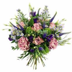 Displayed against a clean white backdrop, this luxurious hand-tied bouquet looks as though it has just been set down on a bright windowsill overlooking Clerkenwell Road. The arrangement is softly domed and full, built around an abundance of pastel pink roses whose petals curl outward in layered, silky spirals. Some of the roses remain in tighter buds, offering promise and structure, while others are more open, with edges fading toward a creamy blush that catches the eye. Interlaced with them are plush carnations in muted dusty rose and mauve, their densely ruffled petals introducing a tactile richness that contrasts beautifully with the smoother roses. Rising elegantly from the mass of blooms, tall spires of indigo and violet Veronica add height and rhythm, their slender forms echoing the vertical lines of nearby warehouse buildings converted into studios and galleries. Between these, clusters of deep purple lisianthus lend depth and a velvety softness, while tiny star-like asters in pale lavender and periwinkle drift through the bouquet like a light mist. Fresh greenery weaves all the flowers together: bright chartreuse filler and feathery foliage bring a lively energy, while rounded, silvery-green eucalyptus leaves add a calmer, cooling note. The stems are gathered tightly and tied just above the base, making the craftsmanship visible in the neat, parallel lines of green. This bouquet feels both contemporary and timeless, the kind of design a discerning Clerkenwell florist would create for same-day delivery to offices near Farringdon Station, apartments by St John Street, or as a heartfelt surprise for someone who appreciates subtle colour, layered texture, and thoughtfully composed floral art.