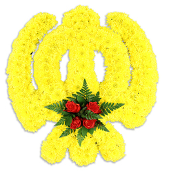 This refined floral composition faithfully renders the sacred Khanda emblem using a sea of bright yellow chrysanthemum heads, each blossom densely packed to outline the circular chakkar, the two sweeping kirpans and the central blade with clear, confident lines against a stark white background. The chrysanthemums give the whole form a soft, tactile surface-like a carefully quilted yellow field-while studio lighting sculpts subtle highlights and a gentle shadow beneath, suggesting the piece rests on an easel or low plinth. At the focal point, where the emblem's elements converge, a concentrated cluster of five deep red roses is nestled among lush, dark green fern fronds; the roses' velvety texture and saturated ruby tone read as a meditative heart, providing visual and emotional counterpoint to the luminous yellow. The arrangement carries a restrained fragrance-green, floral, faintly sun-warmed-and conveys both respect and celebration, suitable for Sikh remembrance services, cultural gatherings or commemorations. As an experienced Clerkenwell florist, we prepare these tributes with sensitivity for families and community groups across Farringdon Road, Leather Lane and nearby St John's Square, mindful of local customs and transport into places of worship or service halls. The workmanship visible here-clean edges, dense packing, balanced scale-speaks to careful mechanics and floral choice, intended to honour tradition while offering a contemporary floral language for civic and private memorials.