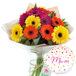 In this carefully composed image, a hand-tied bouquet of Gerbera daisies becomes the vivid heart of a Mother's Day style gift, supported by a single festive balloon, all shown against a crisp white backdrop. The flowers, gathered into a rounded cluster, glow with saturated colour: rich orange, bright lemon yellow, and velvety magenta blooms, each one wide open and perfectly circular, with the familiar dark central eye that defines a gerbera. Their petals radiate in tidy, even layers, giving the arrangement a sense of balance and joyful energy, like a little burst of sunshine brought indoors to a Clerkenwell apartment near St John Street. Deep green foliage nestles between the flower heads, its slightly glossy texture amplifying the vibrancy of the petals. The stems are bound together and wrapped in soft, rustic brown kraft paper that crinkles gently, suggesting a tactile, artisanal touch. Over this, a sheath of clear, shiny cellophane fits snugly, creating small highlights where it catches the studio light. A length of natural twine is tied in a modest bow around the wrapping, reinforcing the bouquet's hand-crafted charm. The arrangement is set into a tall, transparent glass vase filled with water, making the straight green stems clearly visible and giving the design a clean, modern base. To the lower right, a white round foil balloon adds an unmistakable celebratory note. Its surface is decorated with scattered spots of metallic gold and various pink tones, as well as tiny hearts, like confetti tossed in the air. In the centre, the words "best Mum" appear in graceful pink cursive, turning this colourful floral scene into a heartfelt tribute, perfect for same-day flower delivery across the Clerkenwell area.