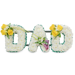 A solemn yet gently uplifting memorial piece spelling "DAD" in substantial, freestanding capital letters, each letter formed from a dense, even blanket of pristine white spray chrysanthemums that create a soft, tactile surface. The edges are neatly defined with a deep, ruffled emerald-green satin ribbon that provides a crisp outline against the white, and slim dark-green metal bars run horizontally behind the letters, revealing the solid support that unifies the trio. On the left 'D' a bright cluster of sunny yellow roses - three to four in full bloom - sits on the upper left curve, complemented by tiny white freesias and fresh green foliage; two slender, bare green stems extend diagonally upward and across toward the centre letter, suggesting movement and connection. The centre 'A' is adorned low on its left diagonal with two striking deep purple calla lilies, their sculptural, trumpet-shaped blooms introducing a refined, contemplative note alongside smaller white accents and leafy greens. The right 'D' mirrors the left with a matching yellow rose cluster on its upper right curve, creating a balanced, symmetrical tribute. Lit in soft, neutral light and set against a plain white backdrop, the textures-ruffled ribbon, plush chrysanthemums, glossy calla petals and delicate freesias-are clearly readable and emotionally resonant. This arrangement, crafted with the care you'd expect from a local Clerkenwell florist, is intended as a dignified funeral or memorial tribute, offering both visual comfort and a quiet fragrance. Clerkenwell Flowers prepares similar bespoke pieces for services around Farringdon, St John's Street and the Leather Lane area.