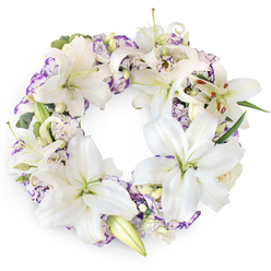 Centered against a crisp, bright white backdrop, a perfectly formed circular wreath radiates gentle elegance and quiet consolation. The ring is lavishly filled with white Oriental lilies, their long, velvety petals unfurling in layers to frame a soft green heart and a cluster of upright stamens dusted with rust-gold pollen. Some flowers are in full, generous bloom, while others are just beginning to open, their buds still smooth and tapered, adding a sense of natural movement and unfolding time. Nestled among the lilies are clusters of lisianthus, their double, ruffled petals edged in shades of pale violet and muted purple, like a soft watercolour wash that cools the brightness of the white. Here and there, sprigs of fresh foliage and slender green leaves weave through the arrangement, offering contrast and a feeling of life and renewal. The composition has a hushed, almost chapel-like calm, reminiscent of stepping away from the bustle of Farringdon Road into a quiet Clerkenwell side street or a peaceful corner near St John's Square. Crafted for moments of loss, this funeral wreath speaks in a low, compassionate voice, expressing sympathy and remembrance without excess. The pure white lilies evoke innocence, peace, and farewell, while the gentle purple tones echo dignity and reflection. Designed for memorial services, wakes, or church funerals in and around Clerkenwell, this floral tribute offers a comforting, continuous circle of blooms, symbolising unbroken love, cherished memories, and the hope that those we lose remain with us in spirit.