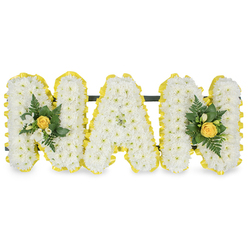 A tender, lyrical letter tribute created to honour a beloved grandmother, this hand-formed MAM uses a dense covering of pristine white chrysanthemum sprays that give each capital letter a soft, cloud-like texture. At either end, mellow yellow rose buds are positioned as gentle punctuation, their petals still tightly furled and carrying the faint, sweet scent of fresh roses that blends with delicate white freesia notes-an intimate fragrance suggested even in the stillness of the photograph. Fine bright-green foliage and small sprigs of leaves thread through the accents, adding lively texture and the promise of spring's renewal. Each letter's perimeter is edged with a bright, sunny pleated ribbon that reads like a warm halo, the yellow satin creating a neat, uplifting frame against the immaculate white backdrop. A slim, dark support bar runs unobtrusively behind the upper third of the letters, offering stability for chapel or graveside display while keeping the visual focus on the floral surfaces. The craftsmanship is quietly evident in the neat contours, the balanced placement of accent clusters, and the restrained colour palette that mixes purity with warmth-qualities Clerkenwell Flowers uses when composing tributes for families around Exmouth Market and Clerkenwell Green. The overall mood is one of thoughtful dignity and personal memory, a composition that invites recollection of soft afternoons and shared laughter while serving as a clear, comforting symbol of enduring love for a grandmother.