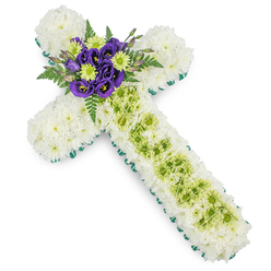 This photograph shows a beautifully composed floral cross tribute, the kind of thoughtful piece often chosen for funeral services and memorials in and around Clerkenwell's historic churches. The cross itself is completely covered in immaculate white spray chrysanthemums, each tiny bloom nestled closely to the next so the surface looks like a soft, continuous blanket of petals, evoking purity, serenity, and a quiet sense of blessing. A crisp edge of fresh green ribbon or neatly tucked foliage frames the entire outline, following the arms and length of the cross with a clear, defined border that makes the Christian shape stand out clearly against the plain white backdrop. Running down the centre of the vertical arm, a panel of lime-green button chrysanthemums adds a gentle lift of colour, like a path of light cutting through the white. Over this green strip, slender pale wires form a delicate, almost lace-like criss-cross pattern, introducing another layer of detail that speaks of careful craftsmanship. At the intersection where the arms meet, a vivid cluster of flowers becomes the heart of the design: rich purple lisianthus blooms, with their velvety petals and softly ruffled edges, sit alongside bright lime-green button mums, while dark green fern fronds curve gracefully around them. This burst of purple and green gives emotional depth to the arrangement, symbolising remembrance, love, and enduring hope. The tribute feels calm and reverent, a floral cross that would sit beautifully in a Clerkenwell chapel or at a local crematorium, offering a tender way to share sympathy and honour a life well lived.