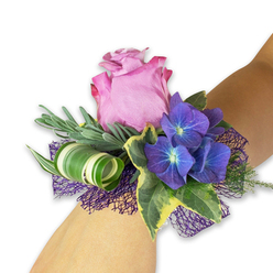 A soft halo of floral charm surrounds this wrist corsage, where careful craft meets garden-fresh sensibility on a light-skinned wrist. The dominant bloom is a lush mauve rose, its petals unfurling in a creamy spiral with a barely-there sheen like morning dew, inviting a gentle touch. Beside it, saturated indigo hydrangea clusters sit like small constellations, their petals rimmed in cool blue and pulsing with a deep pigment that anchors the palette. Silvery-green sprigs-suggestive of eucalyptus or lavender-form a feathery backdrop, their subtle scent lifting the rose's sweetness and adding a hint of herbal clarity. Variegated ivy slips through the arrangement, the glossy leaves offering contrast with dark green centers and pale, butter-coloured margins for a traditional, refined note. A modern flourish arrives in the form of a wide, striped leaf tightly curled into a sculptural loop, its white-green banding providing an elegant, contemporary twist. The whole composition rests on a dark purple, open-weave mesh that peeks out like midnight tulle, giving depth and a faint sparkle under soft light. Texturally the piece is a study in contrasts: the silky rose, the velvet-petaled hydrangea, crisp ivy, and the woven netting that lifts the bouquet from the skin. I think of evenings in Clerkenwell near Farringdon Road or Goswell Road when I fasten similar corsages for weddings and proms-the neighbourhood's understated charm mirrors the corsage's quiet sophistication. This wristlet promises to be remembered, fragrant and tactile, an intimate accent for any formal celebration.