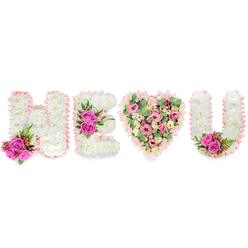 This elegant sympathy or celebration piece reads, from left to right, as the heartfelt message H E [heart] U, crafted entirely of fresh seasonal blooms against a brilliant white backdrop. The three letters-H, E and U-are each formed from compact white chrysanthemums, creating a soft, cushiony texture that suggests peace and purity. Each letter is edged in a delicate blush-pink satin ribbon, ruffled with care, which lends a gentle, handwritten quality to the shapes. Strategic pops of fuchsia roses punctuate the layout: a small arrangement sits at the lower left of the H with slender deep-green foliage and tiny reddish-pink berries; a larger trio accentuates the central arm of the E; and a matching pair of roses adorns the inside curve of the U. The central heart is intentionally more verdant and romantic-the interior is a tapestry of pale pink carnations, creamy blush lisianthus and smaller roses, softened further by sprays of pale green eucalyptus and subtle touches of foliage for depth. The heart's textural variety contrasts with the smooth chrysanthemum letters and creates a focal warmth. In soft daylight, the satin ribbon gleams faintly, the roses release a gentle perfume, and the eucalyptus offers a fresh, clean note. As a local florist in Clerkenwell, I picture this design offered for commemorative services around St John's Square or as a personal keepsake delivered from Clerkenwell Flowers to neighbouring streets-crafted to convey devotion, remembrance, and quiet tenderness with expert finishing and balanced proportion.