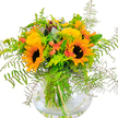 A stunning bouquet arranged in a clear, rounded glass vase welcomes the sun-soaked spirit of Clerkenwell into any room. Two dazzling sunflowers command the ensemble, their wide golden petals and deep centres echoing the energy of Leather Lane on a summer day, surrounded by the shimmery glow of smaller yellow filler flowers-possibly solidago or mimosa-for an extra layer of cheerfulness. Touches of soft coral-orange, suggested by cup-shaped accent blooms peeking from between bold greens, introduce a gentle, contemporary twist that feels equally at home in a modern apartment or classic townhouse. The artistically messy cascade of fern fronds and sprigs of silvery eucalyptus adds an airy, lively edge and a subtle scent reminiscent of a gentle stroll through Myddelton Square Gardens. Bright lime-green leaves interlace with the deeper hues, underscoring the arrangement's freshness and vibrance. Beneath it all, the fishbowl-style vase reveals water-kissed stems, evoking the honest craft and authenticity for which local Clerkenwell florists are known. Bursting with seasonal colour, exuberance, and the uplifting warmth of late summer or a cozy autumn, this bouquet would bring joy to any celebration or simply brighten a grey London day-available for same-day delivery straight from the heart of Clerkenwell.