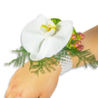 A refined wrist corsage rests gently on a fair-skinned wrist against a pristine white background, presented with the quiet elegance of a piece meant for close inspection. At its center sits a single, large white Phalaenopsis orchid - the moth-like bloom whose broad, satiny petals open in a calm, sculptural curve. The orchid's labellum offers a warm counterpoint: a small, luminous yellow throat with deeper orange-yellow markings that draw the eye like a jewel. Beneath and around the blossom, soft sprays of asparagus fern form a feathered, bright-green cradle, their fine, airy texture lifting the orchid and giving the composition a sense of lightness. To the upper right, a tight cluster of glossy Hypericum berries gives seasonal depth; each bead traces a subtle progression from pale green through rose to a deep cranberry tone, suggesting natural ripeness and a lovely autumnal note. Near the berries, a ruffled, lime-green accent leaf adds a crisp, modern edge and a fresh pop of colour. The whole arrangement is fastened to the wrist by an elegant multi-strand bracelet of small white pearls, their cool luster wrapping comfortably and lending heirloom refinement to the piece. Soft daylight in the photo caresses the petals and highlights the pearl sheen without casting harsh shadows, so every texture - smooth orchid, feathery fern, slick berries, and glossy pearls - reads clearly. This corsage feels timeless and romantic, intended for prom, wedding, or celebratory evenings, and it reads as both a delicate adornment and a handcrafted keepsake, suitable for brides or guests seeking a quiet statement of sophistication in the heart of Clerkenwell.