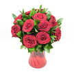 A lush, romantic bouquet of around twelve to fifteen deep crimson red roses is gathered in a rounded, almost dome-like shape and presented in a translucent red glass vase, set against a pristine white studio background that makes every colour seem to glow. Each rose is fully open yet still plump with life, its velvety petals spiralling inward in tight, intricate whorls that create a rich texture you could almost feel with your fingertips. The red is intense and saturated, closer to ruby than scarlet, suggesting a classic, enduring kind of love rather than something fleeting. Between the roses, generous sprigs of glossy dark green foliage, likely ruscus or similar leaves, weave in and out, adding depth and gentle movement to the arrangement. Their waxy surfaces catch the light and provide a cool, fresh counterpoint to the warmth of the blooms. The vase itself has a softly curving silhouette, narrowing towards the base and flaring slightly at the rim, with a subtle ribbed or swirled texture in the glass that plays with reflections. Its red tone echoes the roses without competing, tying the whole composition together. The clean, even lighting creates soft shadows that emphasize the bouquet's fullness, as if it has just been set down on a countertop in a Clerkenwell townhouse or loft near Exmouth Market, ready to surprise someone special. The overall feeling is one of quiet yet unmistakable passion, ideal for anniversaries, Valentine's Day, or any heartfelt declaration of love delivered by a local Clerkenwell florist.