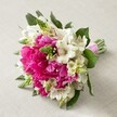 Resting gracefully atop a pale, tactile cloth, this radiant floral bouquet draws inspiration from Clerkenwell's vibrant streets and creative pulse. It features a harmonious gathering of flamboyant fuchsia peonies-each blossom extravagantly full, with ruffled petals layered to perfection, pouring out boundless colour and texture. Illuminating the arrangement, clusters of delicate white Alstroemeria (Peruvian lilies) unfurl, their slender, trumpet-shaped petals accented with fine maroon lines, lending the bouquet a whisper-soft contrast and a sense of airy elegance. Interwoven among the main blooms, vivid green spiky buds-likely fresh Hyacinth or Veronica-add vertical dimension and a playful, modern flair reminiscent of nearby design studios and green urban spaces. Creamy white, delicate filler flowers soften the composition, while dark green foliage weaves through, rooting the entire arrangement in a sense of natural abundance. The bouquet is finished with a bright pink satin ribbon, securely binding the stems and suggesting both readiness and anticipation for a joyful occasion. Every element reflects the authentic craftsmanship and artistry practised daily at local institutions like Clerkenwell Flowers. Ideal as a wedding bouquet, a cherished centrepiece, or an uplifting gift, this arrangement mirrors the neighbourhood's unique harmony of tradition, innovation, and community-perfect for same-day celebrations across Clerkenwell, Farringdon, and nearby Bloomsbury.