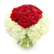 A sophisticated floral design features a compact dome of red roses rising from a plush bed of white hydrangeas, all arranged in a simple, round glass vase, set against a clean white background. The composition is deliberately focused and symmetrical, drawing the viewer's eye first to the roses. Around ten blooms sit closely together, their velvety petals forming perfect spirals of deep crimson. Some roses appear fully opened, revealing generous layers, while others remain slightly cupped, suggesting freshness and careful timing-exactly how a local Clerkenwell florist would prepare a bouquet for a special anniversary delivery near St John's Square. Encircling this intense red core, the hydrangeas spread outward in a generous sphere, creating a soft, pillow-like base. Dozens of tiny, clustered florets make up each hydrangea head, adding texture and volume while maintaining a serene, creamy white tone. The clear, fishbowl-style vase beneath is partially filled with water, giving a glimpse of the green stems gathered together in a tidy bundle, their lines visible through the glass like subtle brushstrokes. The overall lighting is bright and even, with no harsh shadows, allowing the red and white palette to feel crisp and modern. This arrangement conveys quiet luxury and heartfelt devotion, perfect as an anniversary centrepiece for a dinner table in Clerkenwell, a romantic gesture sent to a studio near Farringdon Road, or a graceful floral statement that speaks of commitment, tenderness, and timeless style.