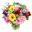 A tall, exuberant bouquet fills a clear glass vase, the arrangement captured against a simple white background so its colours and textures take centre stage. Deep red roses, rich and velvety, form the emotional core of the display, their petals spiralling inward and adding depth and romance. Two bright yellow gerbera daisies with dark brown-orange centres stand out like little beacons of sunshine, radiating happiness in a way that would feel right at home in a Clerkenwell design studio or a light-filled flat near Clerkenwell Green. Gathered around these focal flowers are plentiful pink daisies or chrysanthemums, their soft, many-layered petals and subtle yellow centres creating a cushion of gentle colour and volume that makes the arrangement look wonderfully full. Threaded throughout are elegant purple and lavender lisianthus, their bell-shaped blooms unfurling gracefully and bringing a cool, sophisticated counterpoint to the warm reds and yellows. Small clusters of rounded, glossy red hypericum berries pop up here and there like tiny ornaments, adding a modern textural twist. The whole bouquet is backed and framed by lush greenery, from broad, dark leaves to lighter, delicate sprigs that give a natural, garden-inspired feel while remaining clearly the work of a skilled florist. The transparent vase reveals a careful fan of neatly cut stems and crystal-clear water, grounding the design and showcasing its structure. The mood is upbeat yet refined-perfect for a birthday delivery to an EC1 office, a housewarming near St John's Square, or simply to bring an uplifting burst of seasonal colour into any Clerkenwell home.