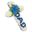 A meaningful floral cross, designed as a funeral tribute for a father, lies at a gentle angle on a clean white background, its colours and textures carefully chosen to convey calm, dignity, and love. The entire cross shape is based in compact white spray chrysanthemums, so closely placed that they create a smooth, plush surface that looks like a soft blanket of petals. This white foundation is neatly edged with a continuous royal-blue satin ribbon, the sheen of the fabric catching the light and lending a formal, almost ceremonial frame to the design, reminiscent of the quiet churches and chapels dotted around Clerkenwell and nearby Holborn. At the intersection of the cross, a striking gathering of royal-blue flowers forms the central spray: full-petalled blue carnations and taller, more slender blue blooms similar to delphiniums or orchids. These are intertwined with dark-green fern fronds and rich green foliage, giving depth, movement, and a touch of natural wildness against the structured cross shape. On the upright stem, the tribute is personalised with the word DAD, carefully shaped from the same blue satin ribbon and set into the white chrysanthemum base so the letters stand out clearly but gently. Soft, even lighting illuminates the piece, making every petal and ribbon fold visible while casting a light shadow that emphasises the three-dimensional form. The overall impression is of a bespoke, thoughtfully made sympathy arrangement that speaks of gratitude and cherished memories, an appropriate choice for a memorial service, church funeral, or graveside farewell for a beloved father within the Clerkenwell community.