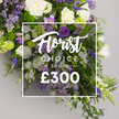 Across the trusted Clerkenwell floristry studio this Florist Choice Special spray stands as a dignified memorial piece. A long generous arrangement flows downward saturated in white and purple with deep greens for contrast. Ivory roses lead the design, their petals smooth and luminous, joined by white lisianthus and pure freesia for a clean delicate texture. Purple accents include deep lisianthus lilac eustomin a and slender delphiniums that rise in graceful layers, while lavender stock lends soft scent and feathery movement. The foliage is lush with ferns and eucalyptus like leaves filling the gaps, giving the spray body and a garden like feel. The backdrop is a neutral grey allowing the bouquet color story to breathe. A white translucent overlay sits over the center bearing Florist Choice Special in graceful script and SPRAY in bold uppercase beneath, with the price ?300 in large white numerals. The image communicates a premium hand crafted option perfect for a funeral memorial or a meaningful gift offered with Clerkenwell Flowers attentive service, including same day delivery to homes or funeral directors across Clerkenwell Farringdon and surrounding boroughs.